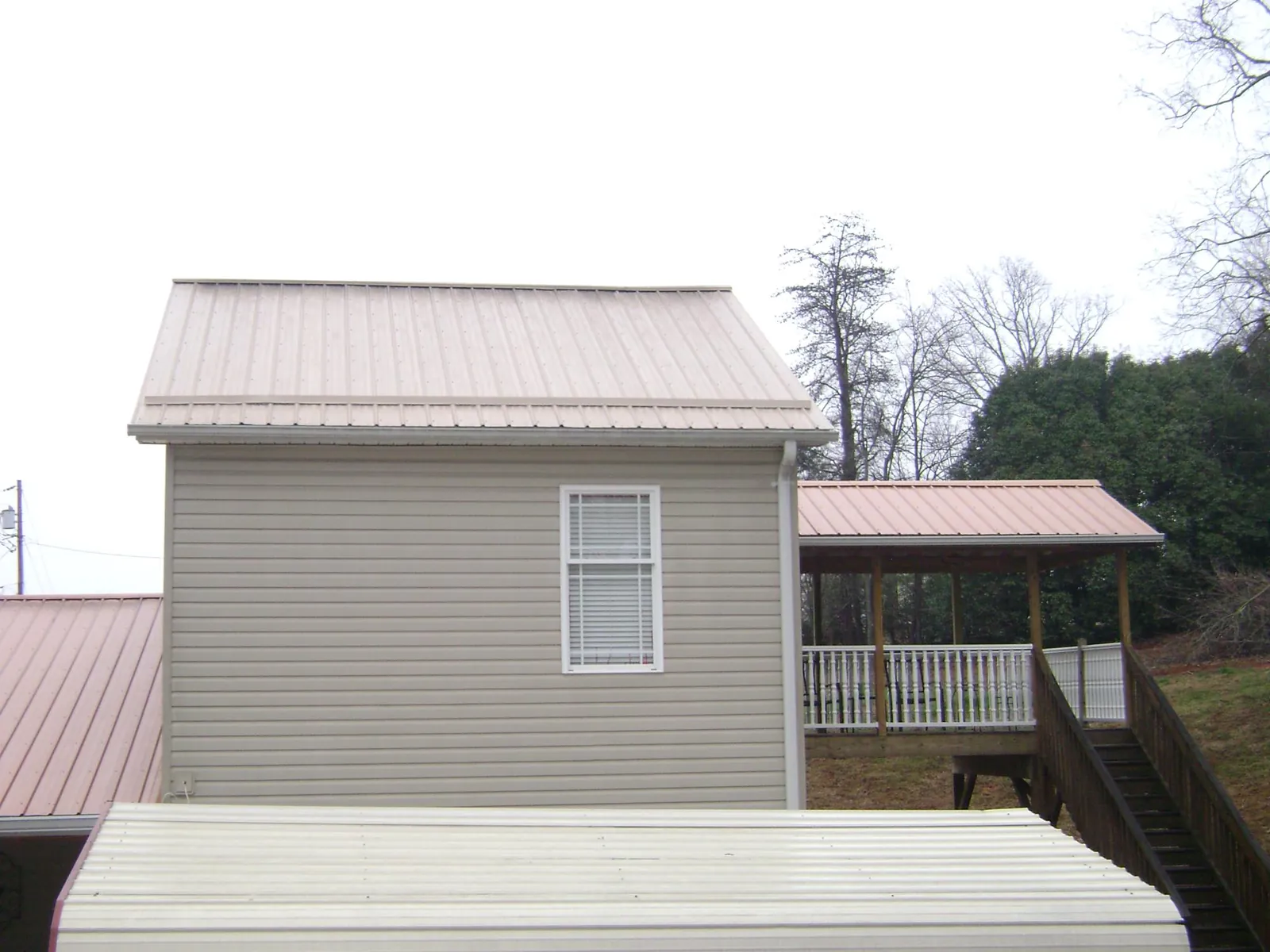 Tan metal roofs on a two story addition and attached porch, from a Roof Replacement job in Star